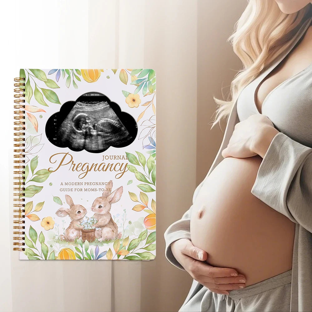 Expectant mum writing in pregnancy memory journal at home